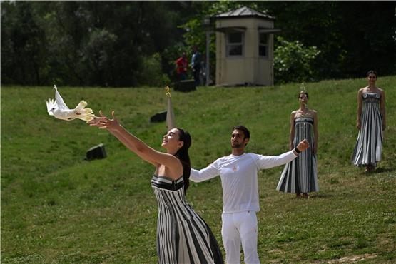 A white dove is released as first torch bearer, rowing Olympic gold medalist on 2020, Stephanos Ntouskos (2L), holds the Olympic torch following the flame lighting ceremony for the Paris 2024 Olympics Games at the Ancient Olympia archeological site, birthplace of the ancient Olympics in southern Greece, on April 16, 2024. (Photo by Aris MESSINIS / AFP) ARIS MESSINIS