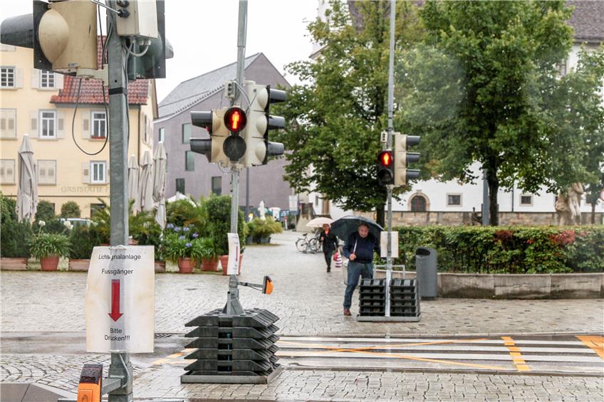 Der Mann mit Schirm fordert per Knopfdruck Grün für die Fußgänger. Der Zebrastreifen, der ihm Vorrang vor den Autos gäbe, ist mit gelben Klebestreifen zur Fußgängerfurt gemacht. Bild: Fleischer