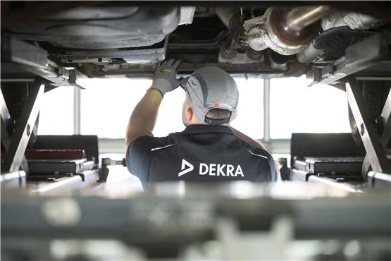Ein Mitarbeiter der Prüforganisation Dekra untersucht im Rahmen einer Hauptuntersuchung (HU) ein Kraftfahrzeug auf einem Prüfstand. Foto: Marijan Murat/dpa