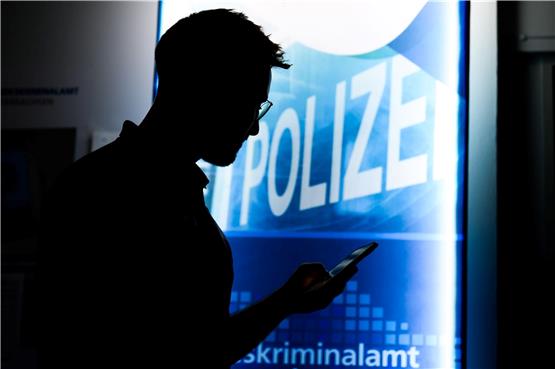 Ein Polizist steht mit einem Smartphone in der Präventionsstelle Cyberkriminalität. Foto: Julian Stratenschulte/dpa