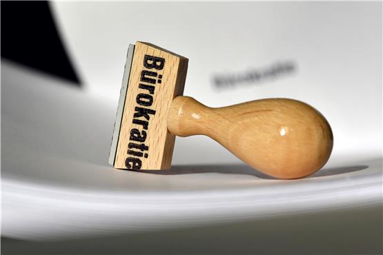Ein Stempel mit der Aufschrift „Bürokratie“ liegt auf Papieren. Foto: Ralf Hirschberger/dpa-Zentralbild/dpa