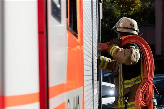 Eine Einsatzkraft der Feuerwehr nimmt während eines Pressetermins einen Schlauch aus einem Einsatzfahrzeug der Feuerwehr Stuttgart (gestellte Szene). Foto: Anna Ross/dpa