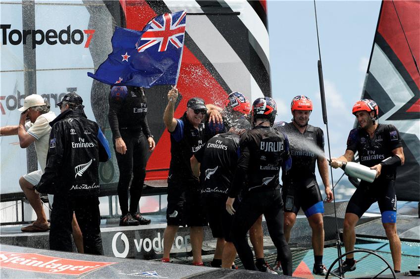 Feuchtfröhliche Siegesfeier vor Bermuda: Die neuseeländische Mannschaft um Steuermann Peter Burling ließ noch auf dem Wasser die ersten Champagner-Korken knallen. Foto: dpa