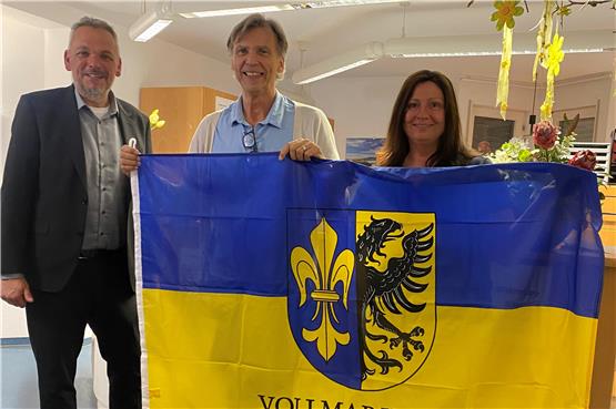 Ortsvorsteher Daniel Steinrode (links) schenkte Markus Ziegler und der leitenden Erstkraft Sabine Schmelzle eine Vollmaringen-Fahne.Privatbild
