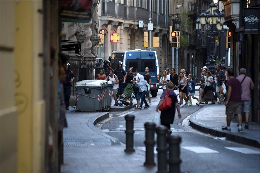 Passanten flüchten in Barcelona in eine Seitenstraße, nachdem auf dem „Las-Ramblas-Boulevard“ ein Lieferwagen in eine Menschenmenge gerast war. Bei dem Attentat, das die IS-Terrormiliz für sich reklamierte, wurden ein Dutzend Menschen getötet, 80 weitere verletzt. Foto: Giannis Papanikos/AP/dpa