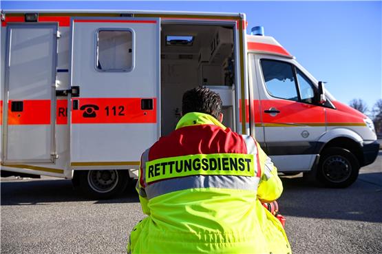 „Rettungsdienst“ steht auf der Jacke eines Mannes vor einem Rettungswagen der Feuerwehr. Foto: Jens Kalaene/dpa/Symbolbild
