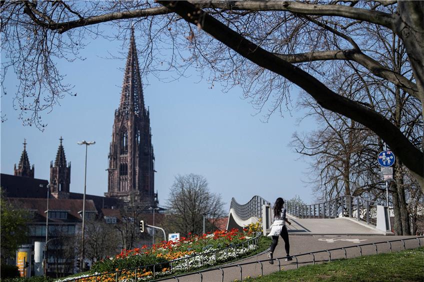 Alleine geht's noch: Joggerin im Stadtpark vor der Kulisse des Freiburger Münsters. Foto: Patrick Seeger/dpa