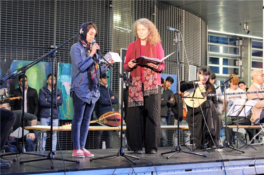 Die elfjährige Tina aus Afghanistan und eine deutsche Choristin, rechts einige der orientalischen Langhalsinstrumente.Bild: Werner