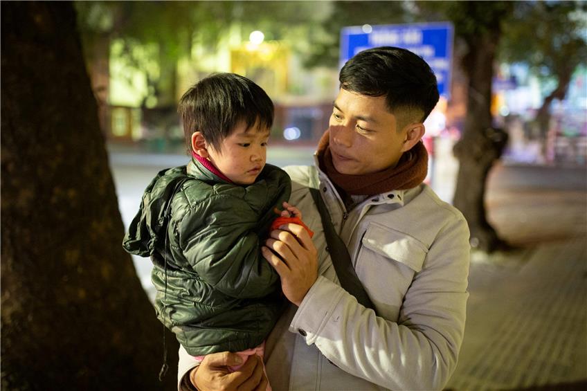 Do Duy Vi, Co-Geschäftsführer der Hilfsorganisation „Blue Dragon Children‘s Foundation“, hält während einer abendlichen Suche nach obdachlosen Kindern in Hanoi einen Jungen auf dem Arm.  Foto: Chris Humphrey/dpa