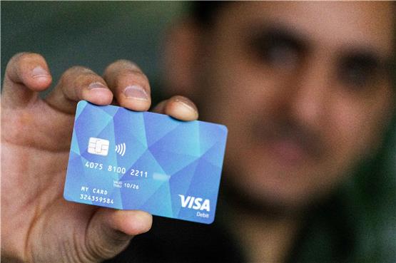 Ein Geflüchteter hält eine Debitcard in der Hand. Bild: Philipp von Ditfurth/dpa
