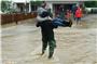 Ein Mensch trägt eine Person durch Hochwasser in Albershausen im Landkreis Göppingen. Foto: Woelfl/SDMG/dpa