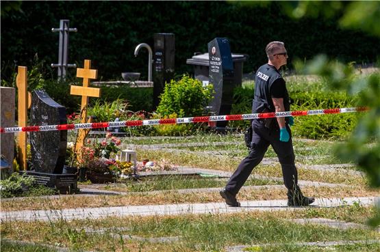 Ein Polizist geht über den abgesperrten Teil an einem Tatort auf einem Friedhof im Juni 2023. Foto: Christoph Schmidt/dpa