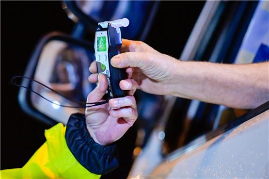 Ein Polizist reicht einem Lastwagenfahrer ein Alkoholmessgerät in die Fahrerkabine. Foto: Uwe Anspach/dpa