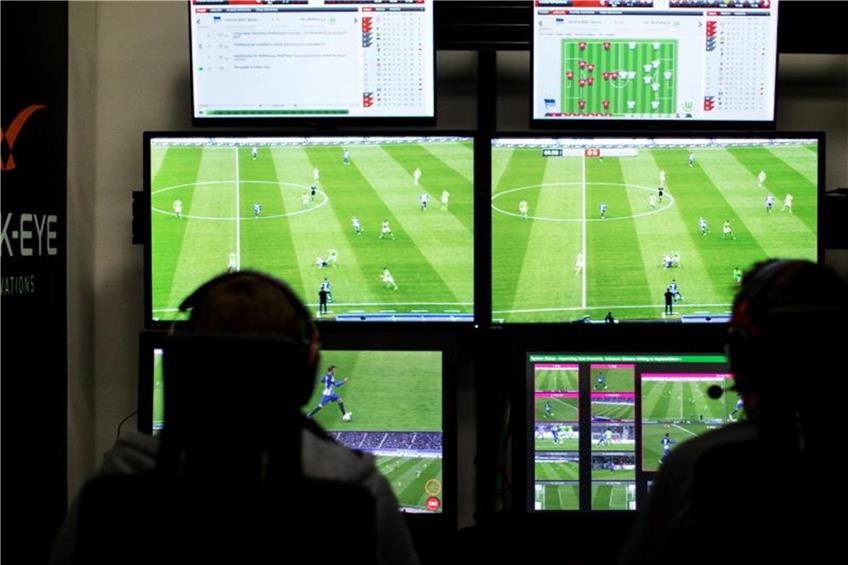 Ein Schiedsrichter und ein Kamera-Operator sitzen vor Bildschirmen, auf denen Fußballspiele übertragen werden. Foto: Marcel Kusch/Archiv dpa/lsw