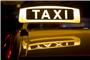 Ein beleuchtetes Taxi-Schild auf einem Autodach. Foto: Daniel Karmann/dpa/Archivbild