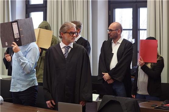 Ein wegen Doppelmordes angeklagter Mann (2.v.l) und seine ebenfalls angeklagte Frau (r), stehen hinter einem der Beihilfe angeklagten Mann (l), in der Anklagebank im Landgericht. Foto: Karl-Josef Hildenbrand/dpa