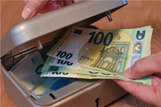 Eine Frau holt Eurobanknoten aus einer kleinen Geldkassette. Foto: Patrick Pleul/dpa-Zentralbild/dpa/Illustration