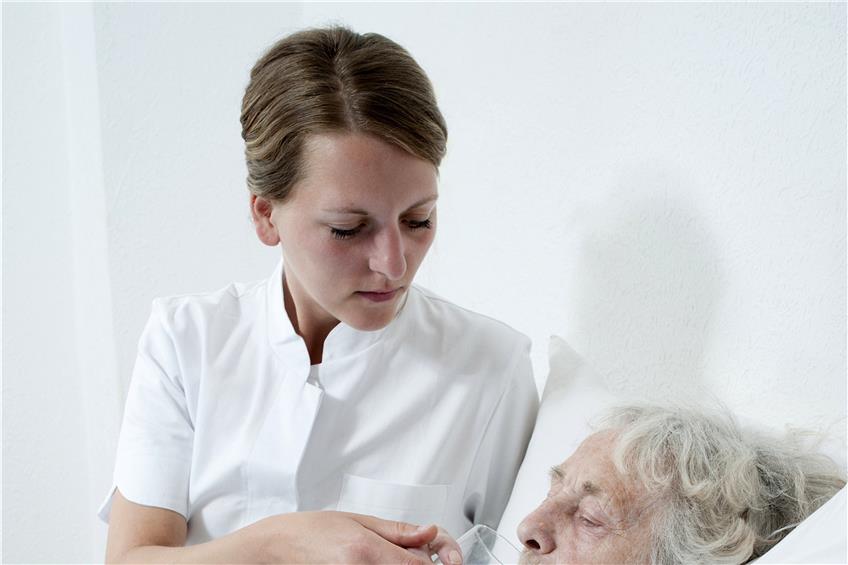 Eine Pflegerin reicht einer alten Frau ein Glas Wasser. Plätze für die Kurzzeitpflege, während Angehörige urlauben, sind aber rar.Bild: Fotolia
