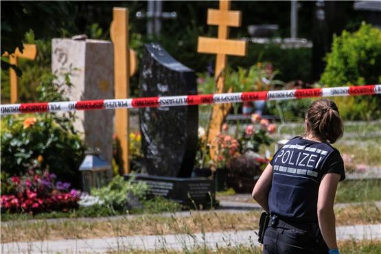 Eine Polizistin geht über den abgesperrten Teil an einem Tatort auf einem Friedhof. Foto: Christoph Schmidt/dpa/Archivbild