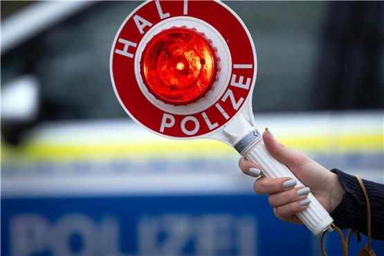 Eine Polizistin hält während einer Verkehrskontrolle an der Berliner Straße eine Polizeikelle mit der Aufschrift „Halt Polizei“. Foto: Soeren Stache/dpa