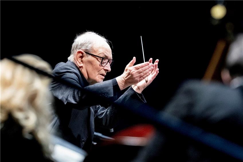 Ennio Morricone bittet auf seiner „Farewell Tour“ 2019 in der Berliner Mercedes-Benz Arena das Tschechische Nationale Symphonieorchester (CNSO) und einen Chor aus 75 Sängerinnen und Sängern, sich zu erheben. Foto: Christoph Soeder/dpa