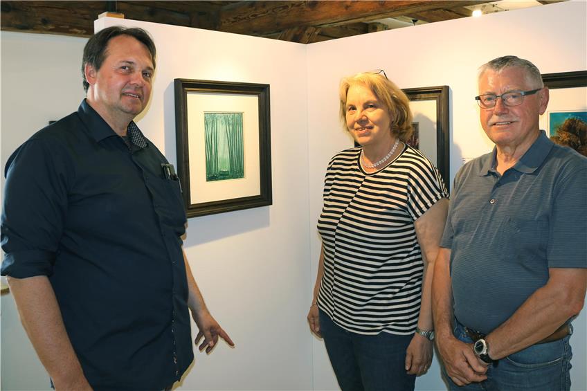 Kurator Ralf Michael Fischer (links), Magdalene und Wilfried Kessler präsentieren das Titelbild der Ausstellung: „Vier Jäger in der Waldlichtung“ von 1988. Bild: Mira Bültel