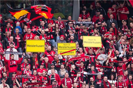 Leverkusener Fans halten Schilder mit der Aufschrift „Meisterkusen“ in die Höhe. Foto: Marius Becker/dpa