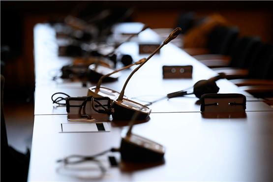Mikrofone und Kopfhörer auf einem Tisch in einem Gerichtssaal. Foto: Jonas Walzberg/dpa/Symbolbild
