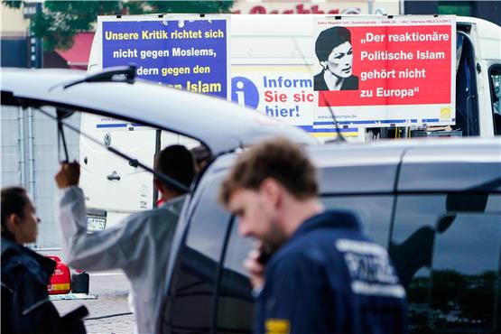 Plakate eines Standes steht hinter Polizisten auf dem Marktplatz. Foto: Uwe Anspach/dpa