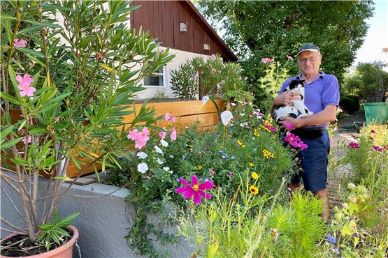 Siegfried Hauser mit seinem Hauskater Moritz inmitten der prächtigen Mössinger Blumenwiese und Oleandersträuchern. Bild: Jana Breuling